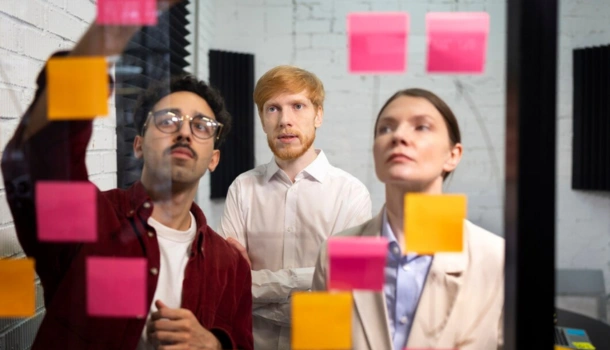 3 people looking at post-it notes and strategizing